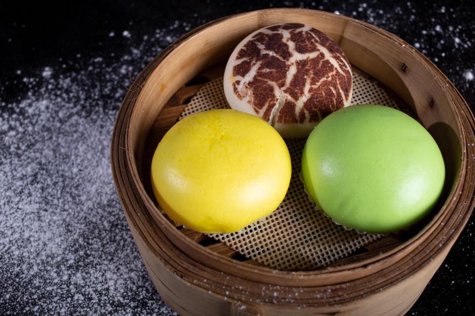 Bamboo steamer containing three bao buns in pyramid formation